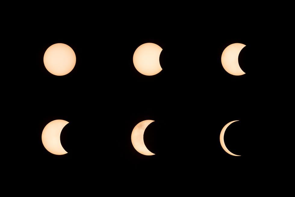 This combination of pictures created on June 21, 2020 shows the moon moving in front of the sun during an annular solar eclipse as seen in Hong Kong. (Photo by ISAAC LAWRENCE / AFP)