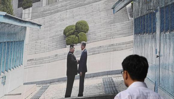 Un hombre camina frente a una pancarta gigante que muestra una imagen del apretón de manos de la cumbre entre el presidente surcoreano Moon Jae-in y el líder norcoreano Kim Jong Un. (Foto: AFP)