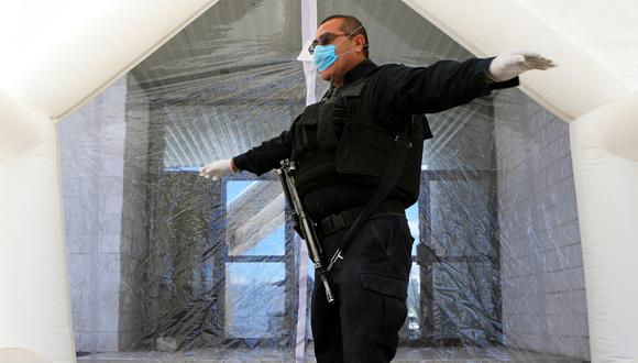 Un policía local se encuentra dentro de un túnel de saneamiento instalado en estaciones de policía para evitar la propagación del coronavirus COVID-19, en Ciudad Juárez, estado de Chihuahua, México. (Foto: AFP/Herika Martínez)