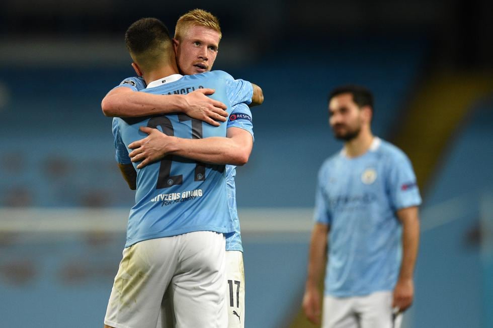 Manchester City's Portuguese defender Joao Cancelo (L) hugs Manchester City's Belgian midfielder Kevin De Bruyne (C) after the UEFA Champions League round of 16 second leg football match between Manchester City and Real Madrid at the Etihad Stadium in Manchester, north west England on August 7, 2020. - Manchester City won the match 2-1. (Photo by Oli SCARFF / POOL / AFP)