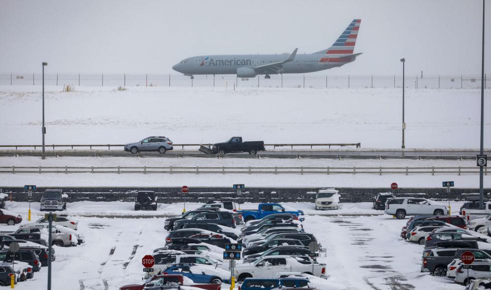 Un avión pasa sobre autos cubiertos de nieve estacionados en el Aeropuerto Internacional de Denver, en Denver, Colorado. Los vuelos fueron retrasados y reprogramados debido a una tormenta de invierno que dejó caer casi un pie de nieve en la ciudad. (AFP)