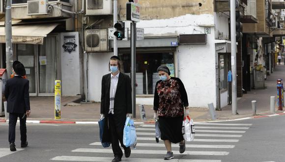 Judíos ultraortodoxos con máscaras protectoras caminan llevando bolsas de compras en la religiosa ciudad israelí de Bnei Brak, cerca de Tel Aviv, durante la nueva crisis pandémica del nuevo coronavirus. (Foto: AFP/Menahem Kahana)