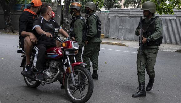 Miembros de la Guardia Nacional Bolivariana (GNB) interrogan a dos hombres que circulaban en motocicleta durante enfrentamientos con presuntos integrantes de una banda criminal en los alrededores del barrio La Cota 905 de Caracas, el 8 de julio de 2021. - Un nuevo enfrentamiento entre policías y Las bandas criminales se han estado produciendo en la capital venezolana desde el miércoles, resultando en al menos cuatro muertes, la mayoría de ellas por balas perdidas, según medios locales. (Foto de Yuri CORTEZ / AFP)