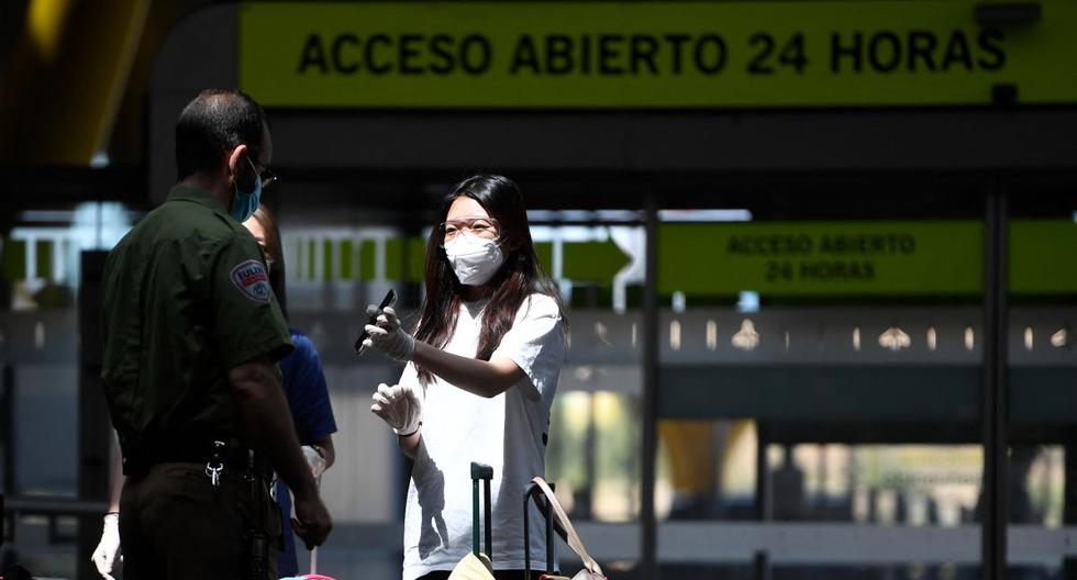 Una pasajera con una máscara facial muestra sus documentos en su teléfono a un oficial de seguridad en el aeropuerto de Barajas en Madrid, España, el 20 de junio de 2020. (PIERRE-PHILIPPE MARCOU / AFP).