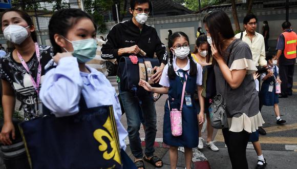 Los padres llevan a sus hijos a la escuela con mascarillas protectoras en Bangkok el 3 de febrero de 2020. (Foto de Lillian SUWANRUMPHA / AFP)