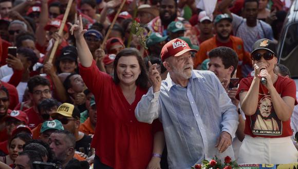 El expresidente de Brasil (2003-2010) y candidato presidencial por el izquierdista Partido de los Trabajadores (PT), Luiz Inácio Lula da Silva (centro), y la candidata a gobernadora de Pernambuco, Marilia Arraes (izquierda), saludan a sus partidarios durante un mitin de campaña en Recife, estado de Pernambuco. Brasil, el viernes 14 de octubre de 2022. (Foto de Maira Erlich / AFP)