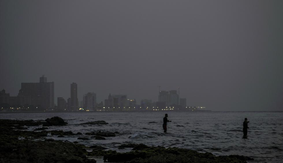 Dos hombres pescan en el mar mientras una nube de polvo del Sahara flota en el aire en La Habana. (AP/Ramon Espinosa).