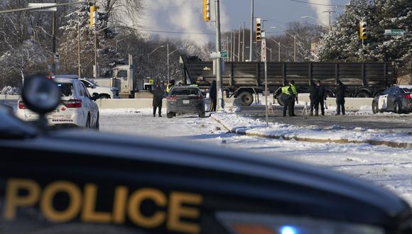 Los oficiales de policía montan guardia en una barricada a lo largo de la carretera que conduce al cruce fronterizo del Puente Ambassador en Windsor, Ontario, Canadá, el 14 de febrero de 2022. (Foto de Geoff Robins / AFP)
