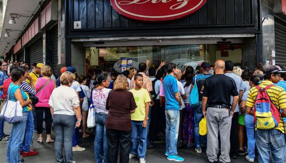 La gente espera afuera de un supermercado durante un apagón en Caracas el 30 de agosto de 2018. (Foto referencial: AFP)