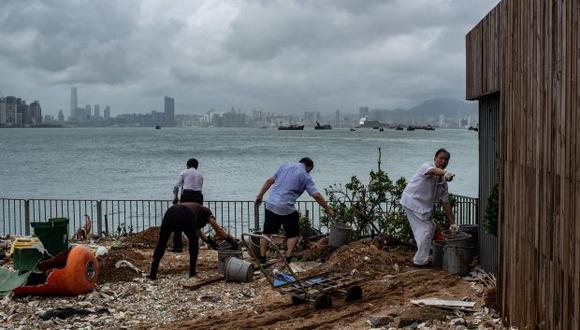 El personal de un restaurante chino limpia escombros y basura en la aldea costera baja de Lei Yue Mun después del tifón Mangkhut en Hong Kong. (Foto: AFP)