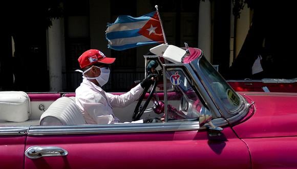 Un taxista privado en un viejo automóvil estadounidense usa una máscara facial como medida preventiva contra la propagación del nuevo coronavirus, COVID-19, mientras conduce a los turistas por La Habana, en Cuba. (Foto: AFP)