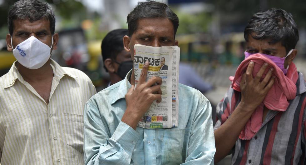 En esta imagen tomada el 9 de julio de 2020, un hombre sostiene un periódico para cubrirse la cara en ausencia de su mascarilla durante la pandemia de coronavirus, en Bangalore (India).  (Manjunath Kiran / AFP).