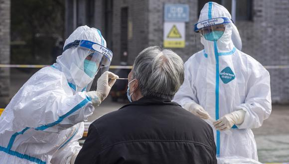 Un trabajador de la salud toma una muestra de hisopo de un hombre para detectar el coronavirus durante una prueba masiva en un centro de pruebas improvisado en Ningbo, en la provincia de Zhejiang. (Foto de AFP)