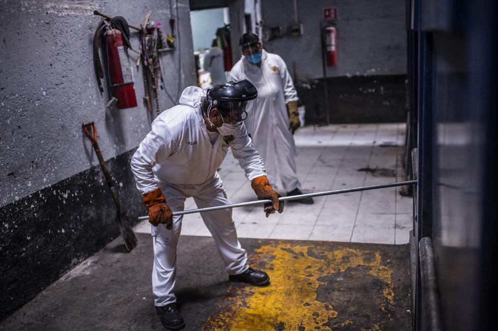 Los empleados del panteón Iztapalapa trabajan durante la cremación de una víctima de COVID-19 en la Ciudad de México. (Pedro PARDO / AFP)