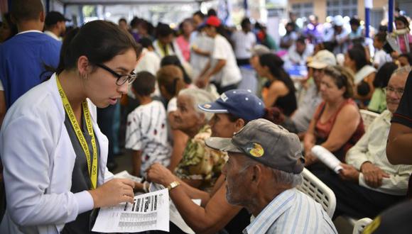 Un voluntario del movimiento "Coalición por la Ayuda y la Libertad" ayuda a las personas a buscar atención médica en el barrio de Macarao, en Caracas. (Foto: AFP)