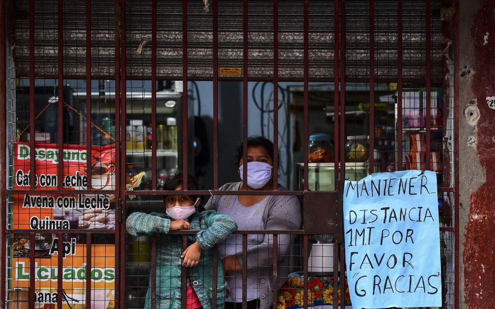 Una mujer y su hija, ambas con mascarillas como medida preventiva contra el nuevo coronavirus, miran a la calle desde una tienda en el barrio de chabolas de Villa 31 en el centro de Buenos Aires. (Foto: AFP/Ronaldo Schemidt)