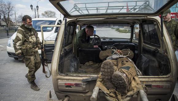Separatista ruso observa el cadáver de un soldado ucraniano.