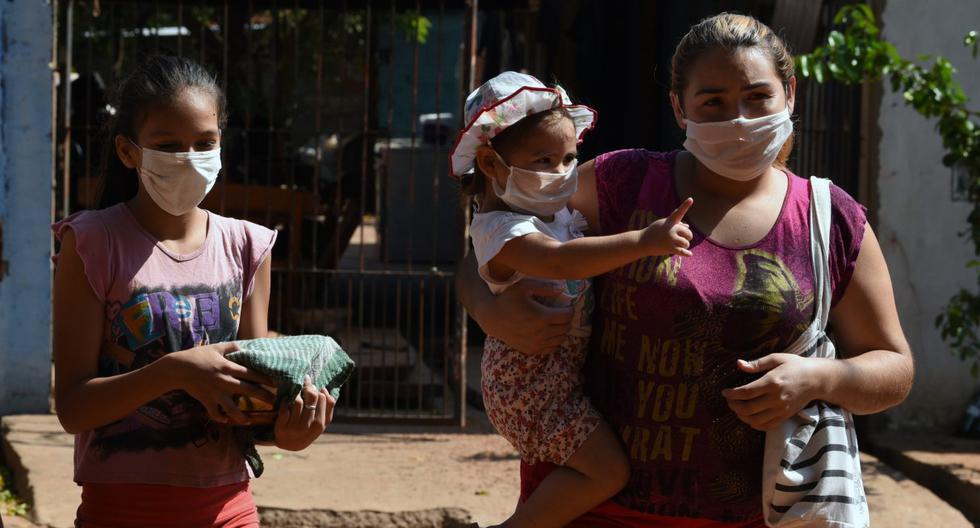 Imagen referencial. Una mujer y sus hijas reciben comida en un comedor para familias vulnerables durante la pandemia del coronavirus, en Asunción, el 4 de mayo de 2020. (NORBERTO DUARTE / AFP).