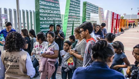 Migrantes centroamericanos, parte de un grupo de 87 personas deportadas de los Estados Unidos, se reúnen en el cruce fronterizo de El Chaparral antes de ser transportados a un refugio en Tijuana. (Foto referencial: AFP)