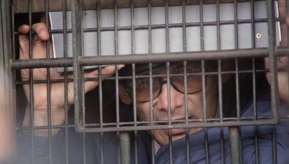 El asesino en serie Charles Sobhraj, acusado en los años 70 de múltiples asesinatos y encarcelado desde 1977, habla con los periodistas detrás de una ventana enrejada el 11 de febrero de 1997. (AFP)