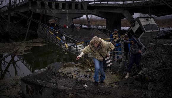Una mujer corre mientras huye con su familia a través de un puente destruido en las afueras de Kiev, Ucrania, el miércoles 2 de marzo de 2022. (Foto AP/Emilio Morenatti).