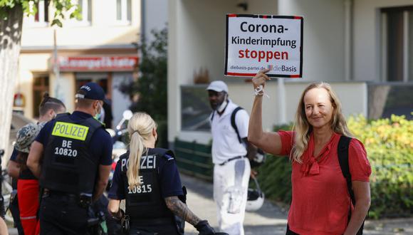Una manifestante antivacuna, simpatizante del partido corona-escéptico "Die Basis" es observada por la policía mientras sostiene un cartel que dice "Alto a la vacunación infantil" en Berlín. (Foto: Odd ANDERSEN / AFP)