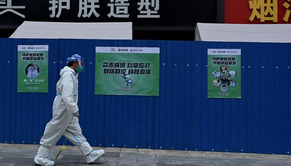 Un trabajador de la salud con equipo de protección personal (EPP) pasa frente a una zona residencial cercada y bloqueada debido a las restricciones del coronavirus  en Beijing el 20 de junio de 2022. (Foto de Noel Celis / AFP)