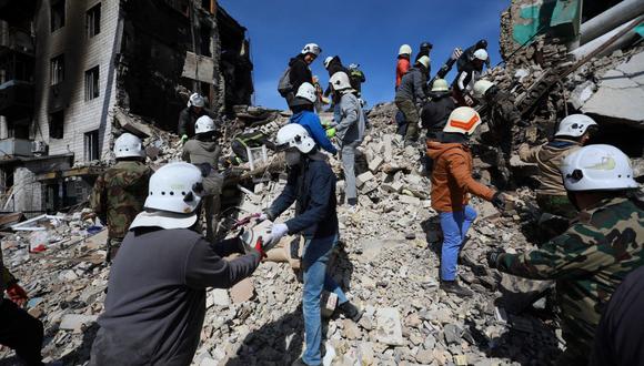Los voluntarios ayudan a los rescatistas a eliminar los estruendos de un edificio dañado en la ciudad de Borodianka, al noroeste de Kiev, el 7 de abril de 2022, durante la invasión militar de Rusia lanzada contra Ucrania. (Foto de Aleksey Filippov / AFP)