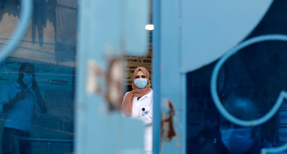 Imagen referencial. Médico palestino de la ONU con mascarilla debido al coronavirus detrás de una puerta en una clínica en el centro de la Franja de Gaza. (AFP / MOHAMMED ABED).