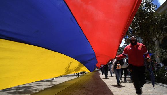 Los trabajadores llevan una larga pancarta que representa la bandera nacional colombiana durante una manifestación del Primero de Mayo (Día del Trabajo) para conmemorar el día internacional de los trabajadores, en Bogotá, el 1 de mayo de 2022. (Foto de Raúl ARBOLEDA / AFP)