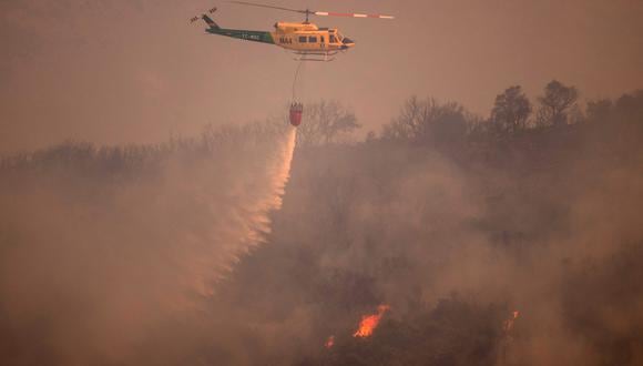 Se muestra un helicóptero desde Alhaurín de la Torre mientras arroja agua sobre un incendio forestal en la Sierra de Mijas, en la provincia de Málaga, el 15 de julio de 2022. (Foto de JORGE GUERRERO / AFP)