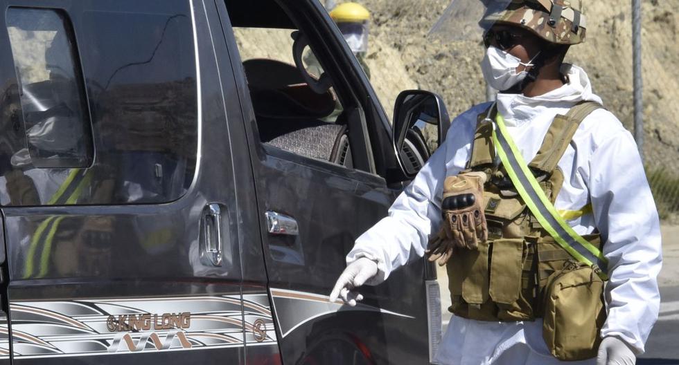 Un soldado con traje de protección detiene una camioneta en un puesto de control en Bolivia, el 20 de mayo de 2020. (AIZAR RALDES / AFP).