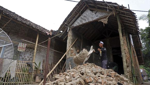 Un residente limpia los escombros de su casa dañada un día después de que un terremoto de magnitud 6,6 azotara el área de la aldea de Kertamukti en Pandeglang el 15 de enero de 2022. (Foto de Dziki Oktomauliyadi / AFP)