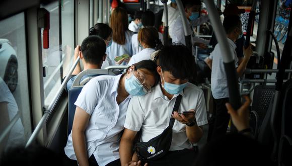 Una pareja luce mascarillas mientras viaja en autobús en Pekín. (Foto: AFP)