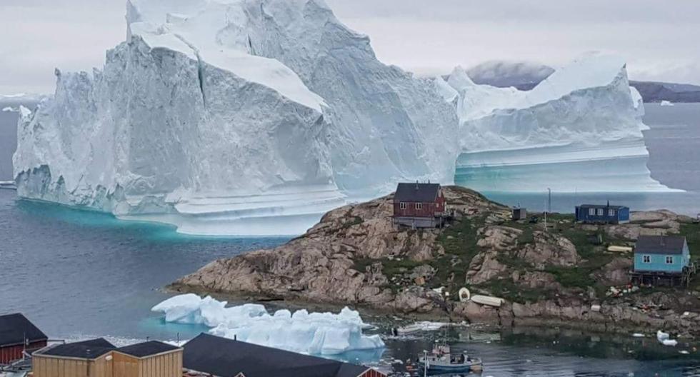 Se ve un iceberg gigante detrás de un asentamiento de Innaarsuit, Groenlandia el 12 de julio de 2018.  (Ritzau Scanpix/Magnus Kristensen/REUTERS).