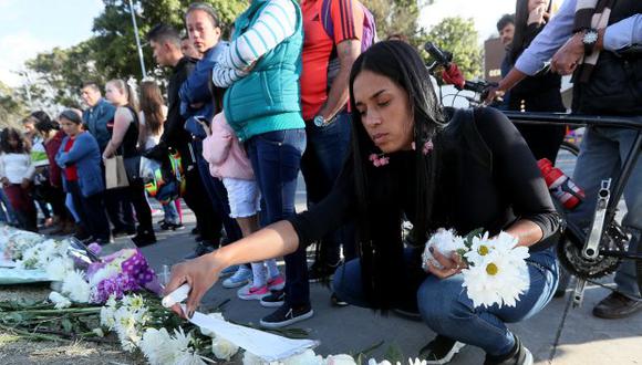 Personas llevando flores y encendiendo velas en honor a los policías fallecidos en el ataque a la Escuela de Policía General Santander. (Foto: EFE)