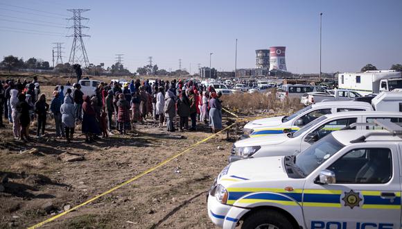 Los residentes del asentamiento informal de Nomzamo reaccionan a la escena del crimen donde 14 personas fueron asesinadas a tiros en una taberna en Soweto el 10 de julio de 2022. (Foto de EMMANUEL CROSET / AFP)