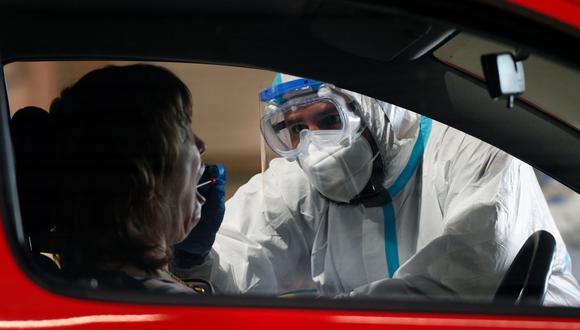 Personal sanitario toma una muestra de la boca del conductor de un vehículo en una estación de pruebas de coronavirus instalada en el antiguo aeropuerto militar de Guetersloh, el pasado 30 de junio de 2020. (AFP / Ina FASSBENDER)