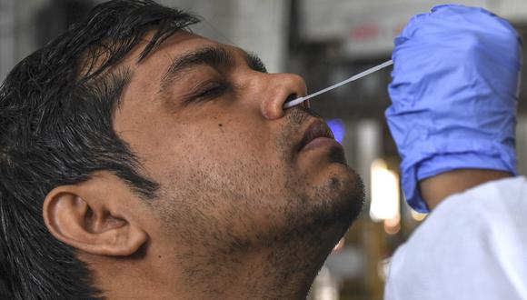 Un personal médico toma una muestra de hisopo de un hombre para una prueba PCR para detección de Covid-19. (Foto: Indranil MUKHERJEE / AFP)