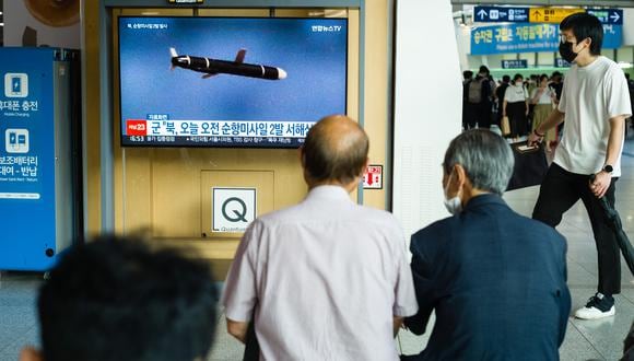 La gente se sienta cerca de una pantalla que muestra una transmisión de noticias con imágenes de archivo de una prueba de misiles de Corea del Norte, en una estación de tren en Seúl el 17 de agosto de 2022. (Foto:  ANTHONY WALLACE / AFP)
