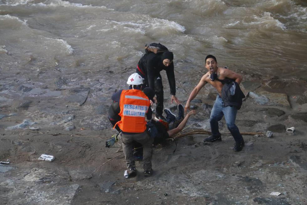 Manifestantes y equipos de emergencia socorren a una persona que se encuentra inconsciente luego de supuestamente haber sido empujado por Carabineros al río Mapocho durante las protestas en contra del gobierno de Sebastián Piñera en Santiago (Chile). (EFE/ Sebastián Silva).