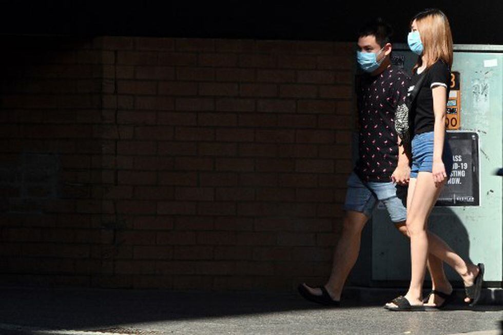 Los residentes utilizan máscaras faciales mientras caminan en el suburbio de Burwood, en Sídney, en medio de la pandemia del nuevo coronavirus. (Saeed KHAN / AFP)