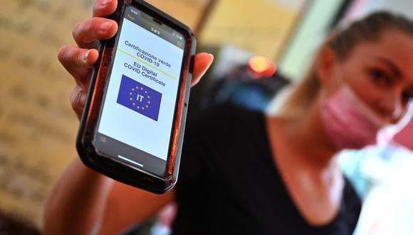 Un cliente muestra su Green Pass en un teléfono móvil en un bar del centro de Roma el 6 de agosto de 2021, cuando Italia lo hizo requerido para ingresar a cines, museos y para comer en el interior de los restaurantes. (Foto: Andreas SOLARO / AFP)
