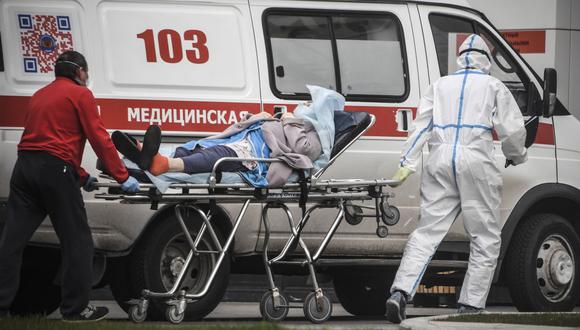 Los trabajadores médicos transportan a una mujer a un hospital donde los pacientes infectados con el nuevo coronavirus están siendo tratados en el asentamiento de Kommunarka en las afueras de Moscú, Rusia. (Foto: AFP/Alexander Nemenov)