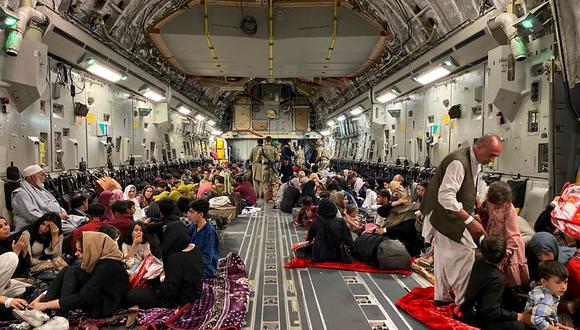 Los afganos se sientan dentro de un avión militar de Estados Unidos para salir de Afganistán desde el aeropuerto militar de Kabul el 19 de agosto de 2021. (Shakib RAHMANI / AFP).