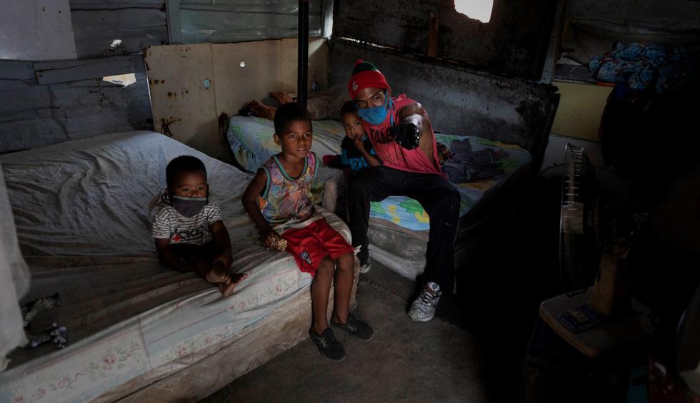 Foto de José Gregorio Machado, de 29 años, junto a sus hijos dentro de su vivienda en un terreno ocupado en Caracas (Venezuela). (EFE/ Rayner Peña R.).