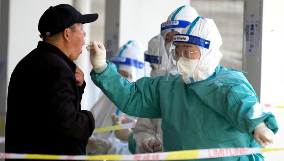 Un trabajador de la salud obtiene una muestra de hisopo de un hombre para realizarle la prueba del coronavirus Covid-19 en un sitio de recolección de hisopos en Beijing el 21 de marzo de 2022. (Foto de Noel Celis / AFP)