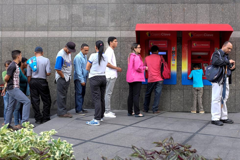 La gente hace cola para retirar efectivo de cajeros automáticos en una sucursal del Banco de Venezuela, en Caracas. (Reuters)