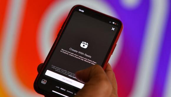 Esta imagen ilustrativa muestra la nueva función de video de Instagram "Reels" en un teléfono inteligente frente a una pantalla que muestra el logotipo de Instagram. (Foto: Chris DELMAS / AFP)