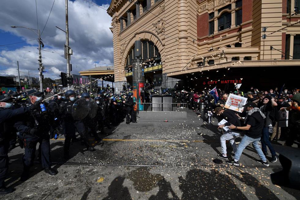 Los ciudadanos son rociados con gas pimienta por la policía durante una protesta anti-cierre en el distrito central de negocios de Melbourne, Australia, 21 de agosto de 2021. (EFE/EPA/JAMES ROSS).